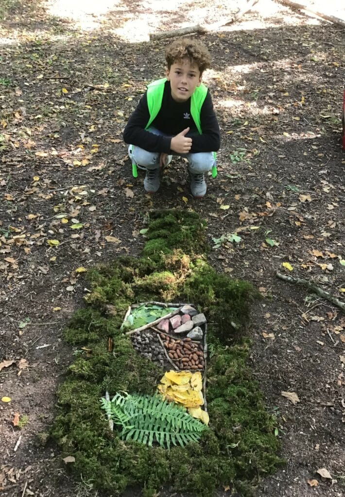 un élève devant une figure composée de mousse, de feuilles et autres